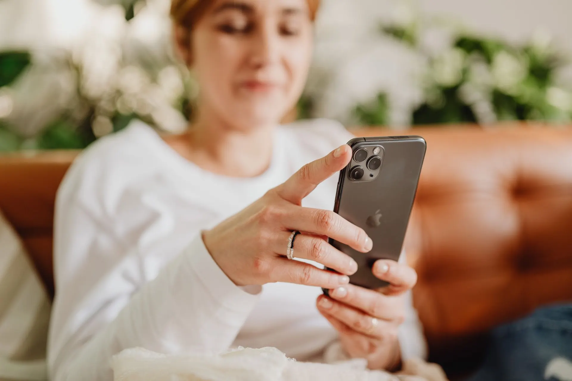 Žena na gauči prochází v mobilu nabídky