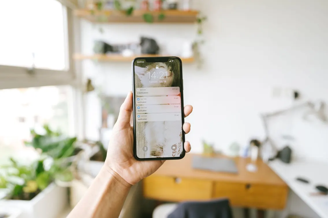Ruka drží telefon s upozorněními na obrazovce